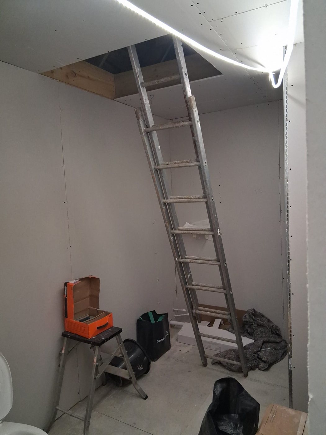 Plasterboarded room with a ladder up to the roof opening before tiling started