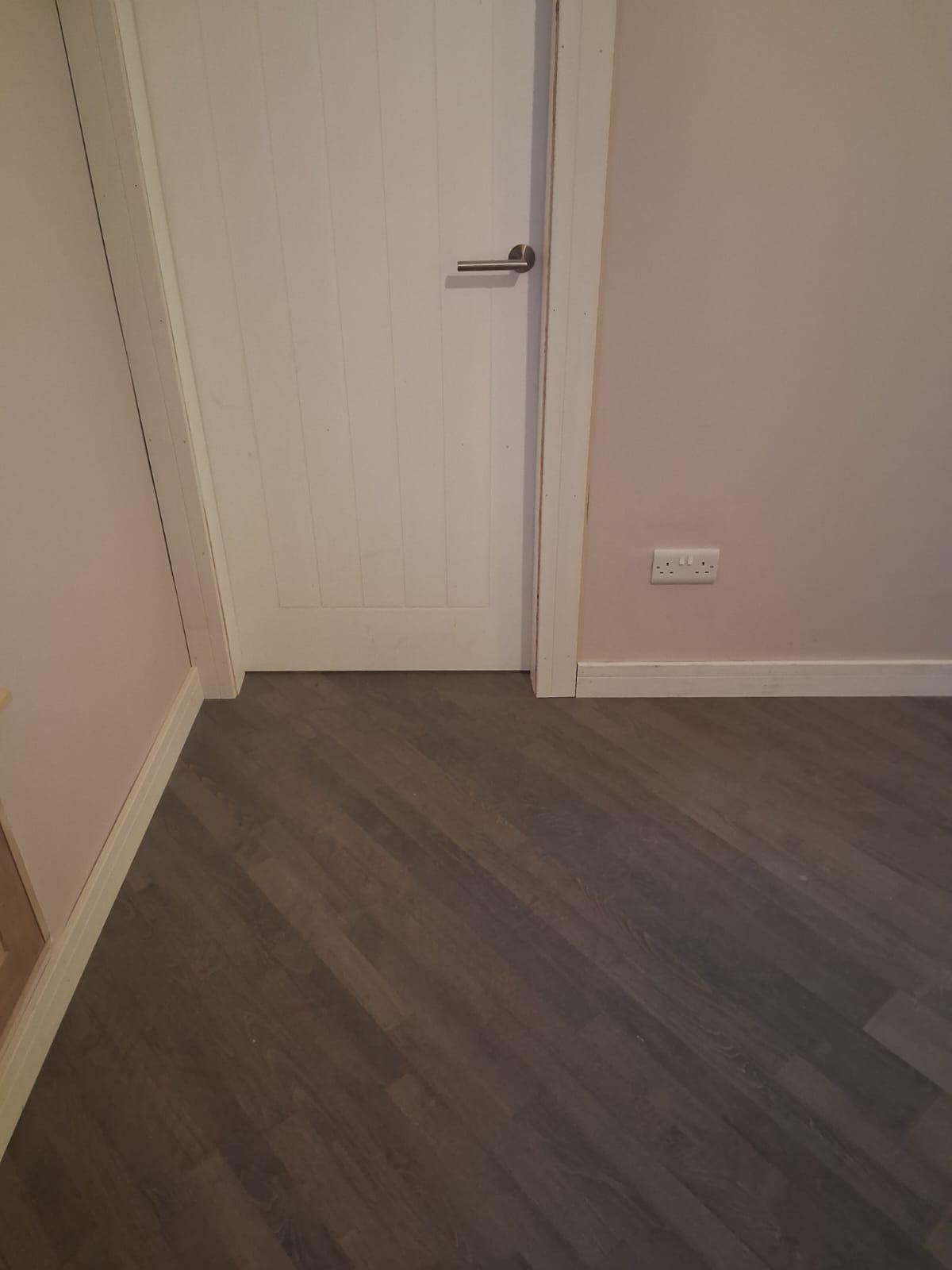 Hardwood boards cut in to the door lining and skirting in front of a white panelled door