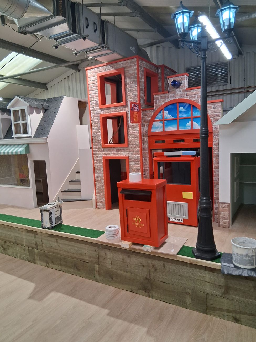 Play village fire station and post office frontage with a red post box and a lit lamp post